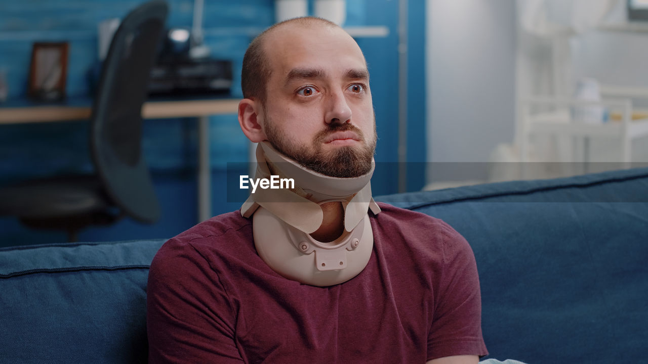 Man with neck brace sitting at home