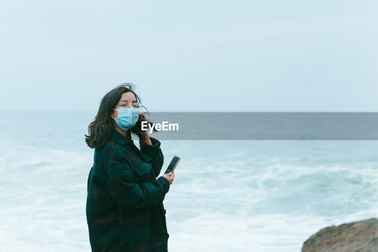 side view of young woman looking at sea against clear sky