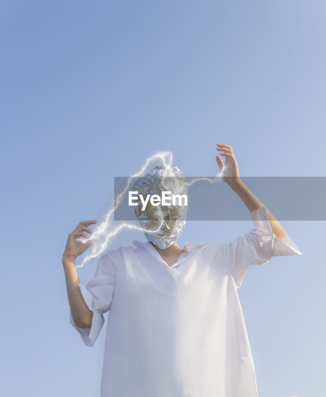 portrait of young woman with arms raised standing against clear sky