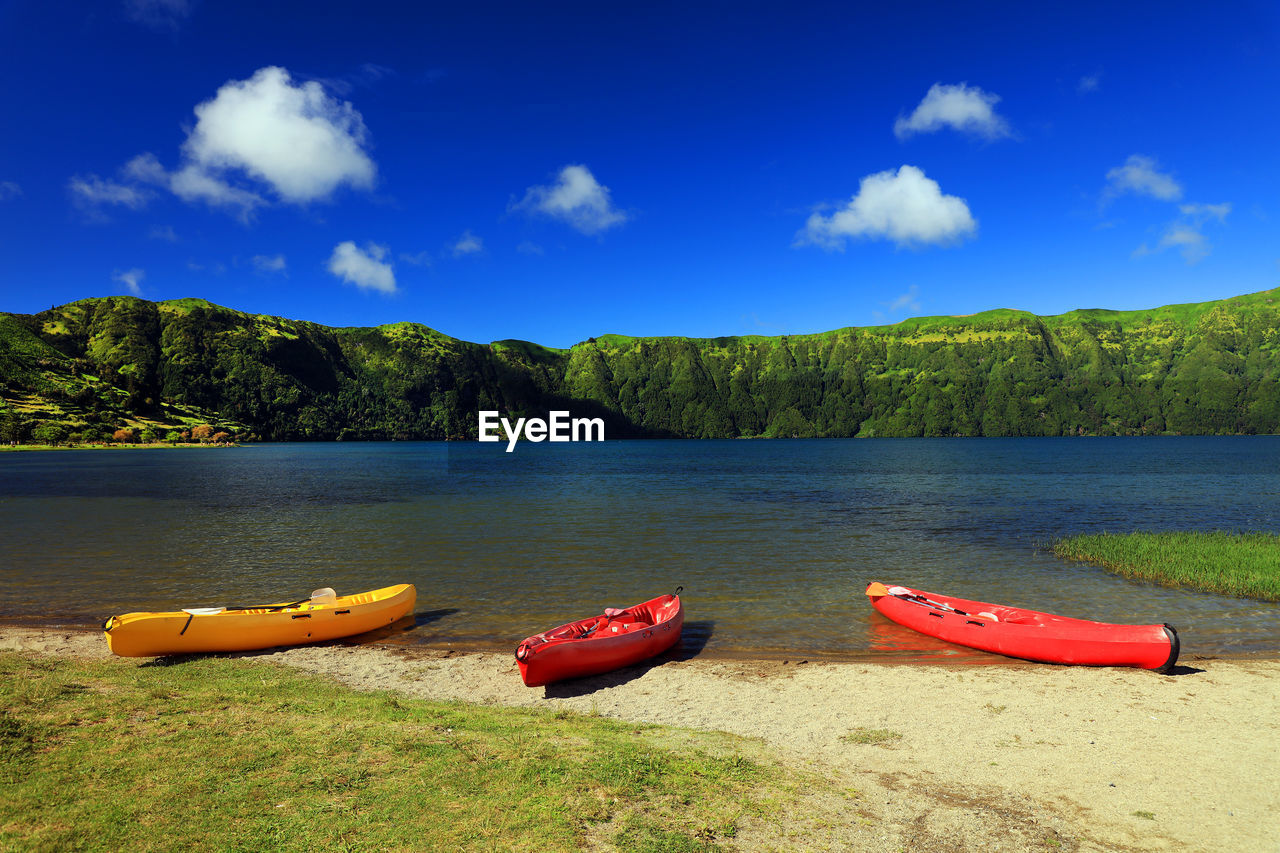 BOATS MOORED BY LAKE AGAINST SKY