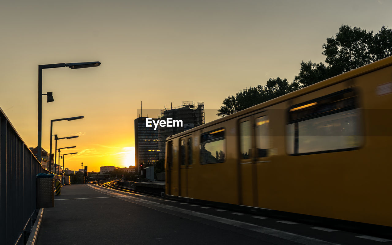 Train on road in city against sky during sunset