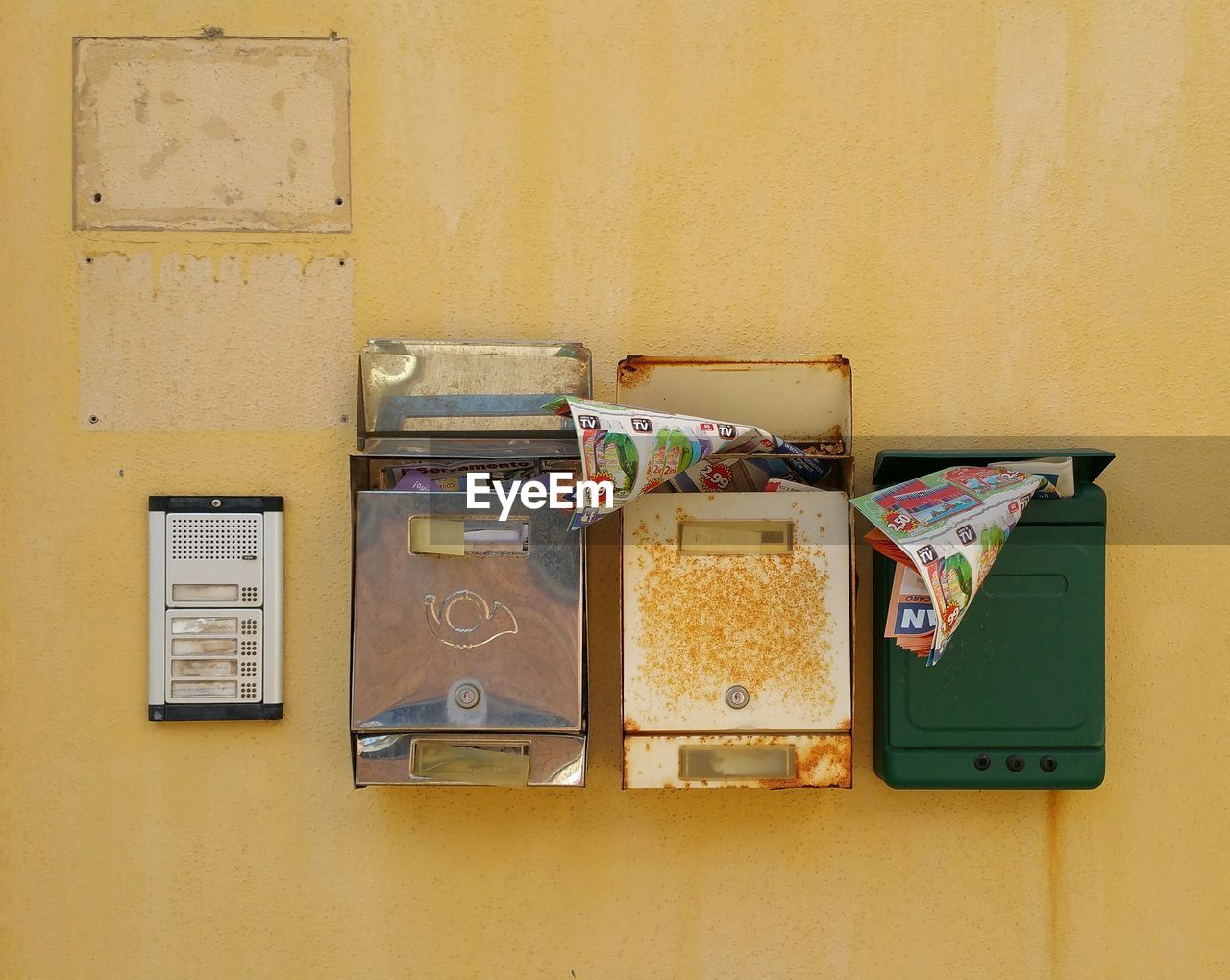 Magazines in mailbox against yellow wall