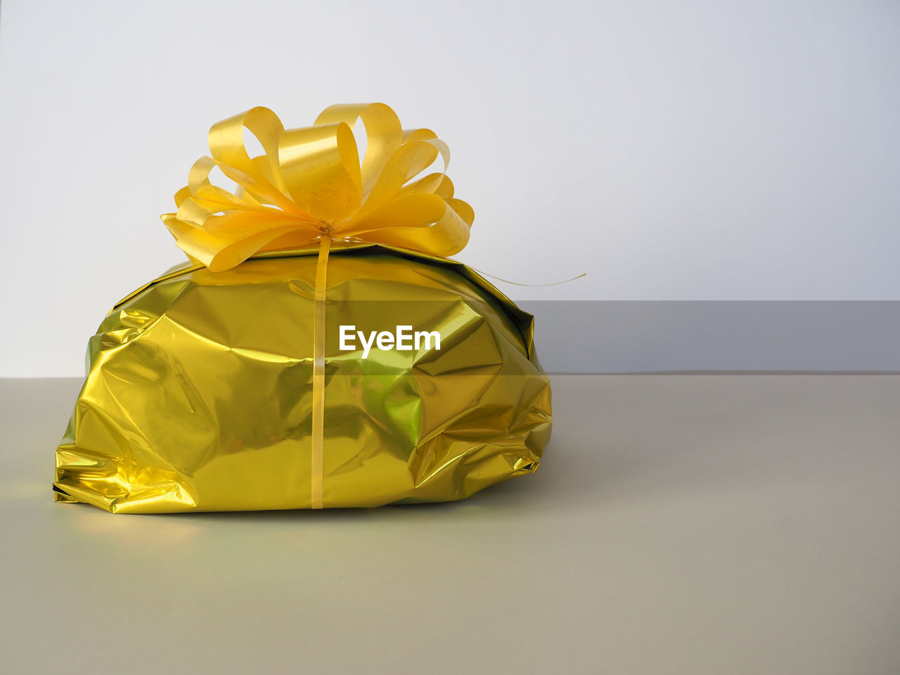 yellow, gift, ribbon, bow, celebration, tied bow, present, gold, wrapping paper, surprise, paper, studio shot, holiday, wrapped, indoors, copy space, box, gift box, no people, single object, art, christmas, container, event, wedding favors, emotion, still life, flower, petal, gray background, decoration