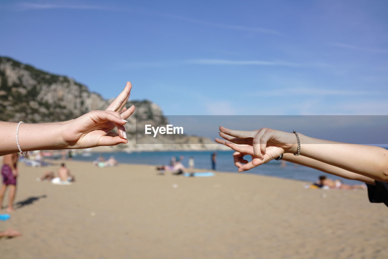 Midsection of people on beach against sky