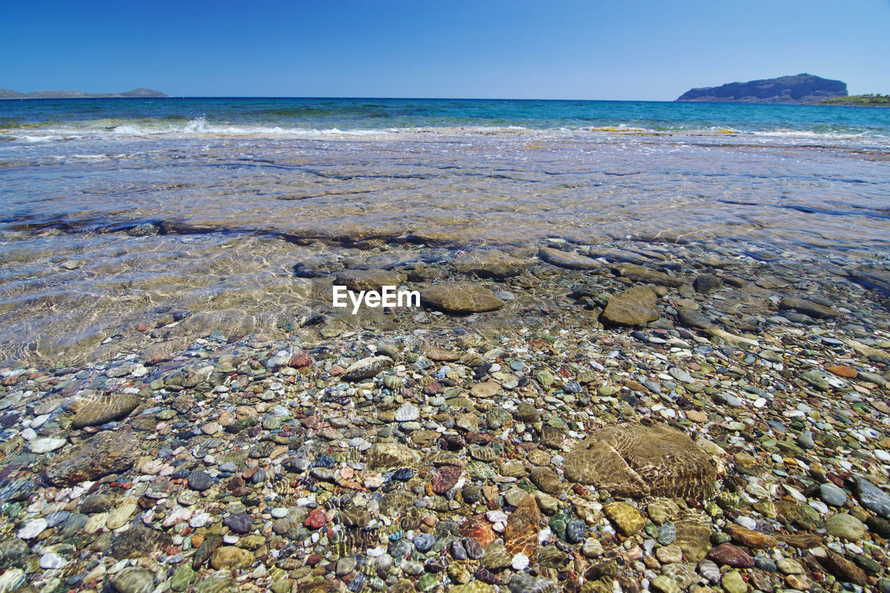 SURFACE LEVEL OF PEBBLE BEACH AGAINST SKY