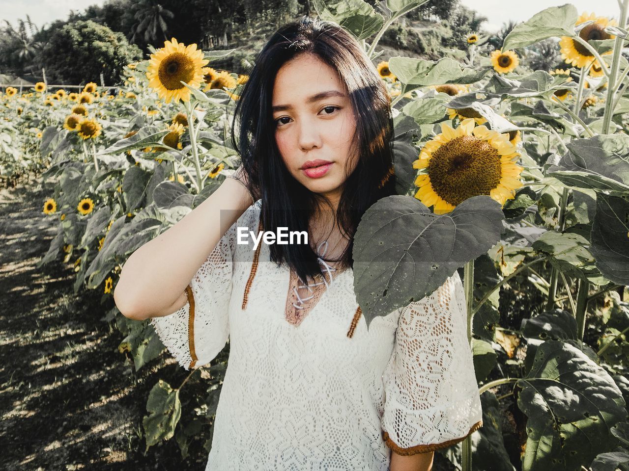 PORTRAIT OF BEAUTIFUL YOUNG WOMAN STANDING WITH FLOWERS