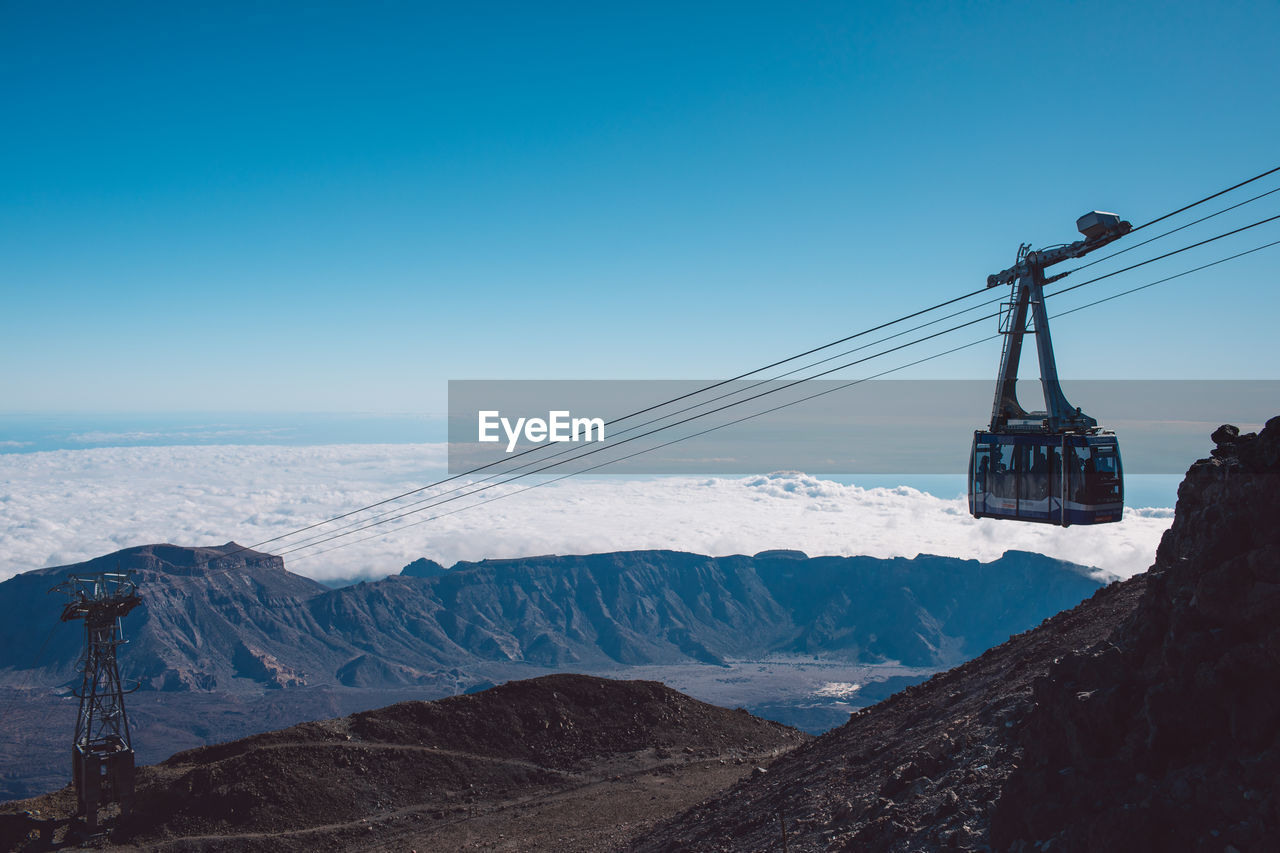 OVERHEAD CABLE CAR OVER SNOWCAPPED MOUNTAINS AGAINST SKY