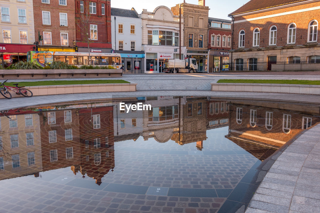 REFLECTION OF BUILDINGS ON PUDDLE IN STREET