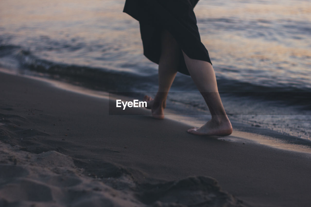 Low section of woman walking at beach