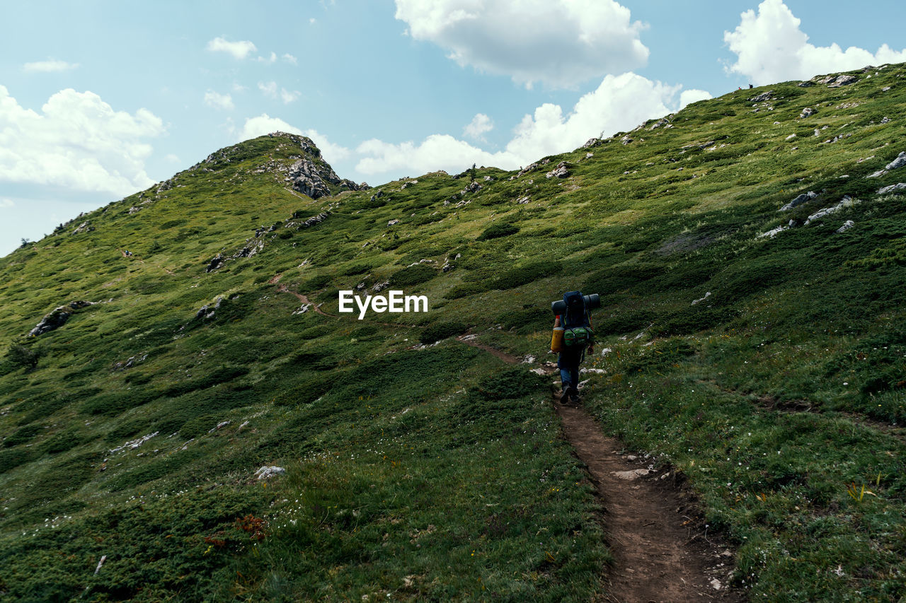 Rear view of man walking on mountain against sky. shot in stara planina, bulgaria.