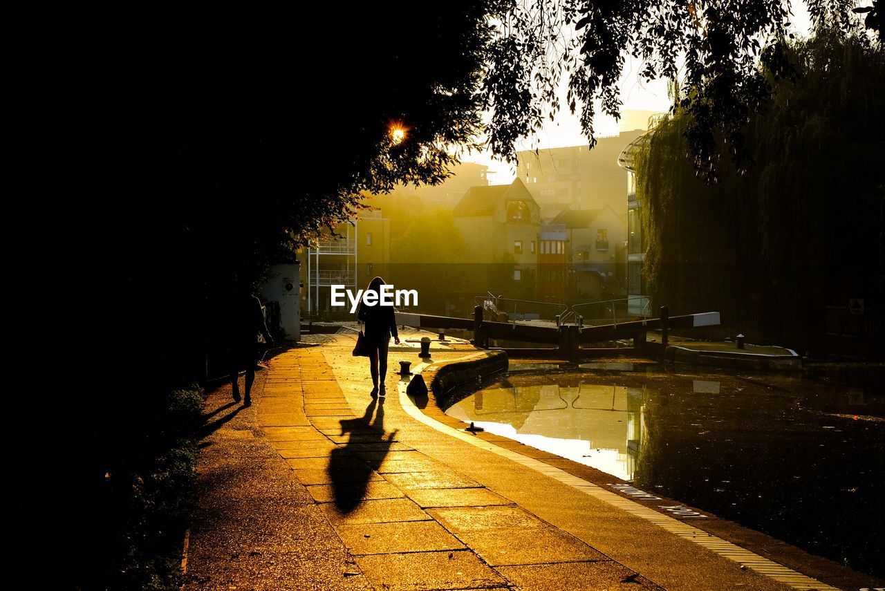 People walking by  canal and lock in city