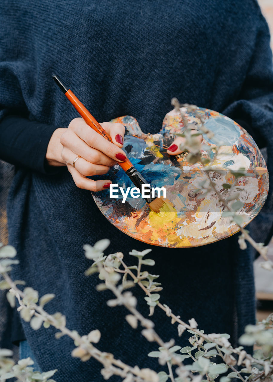 Midsection of woman holding artist palette