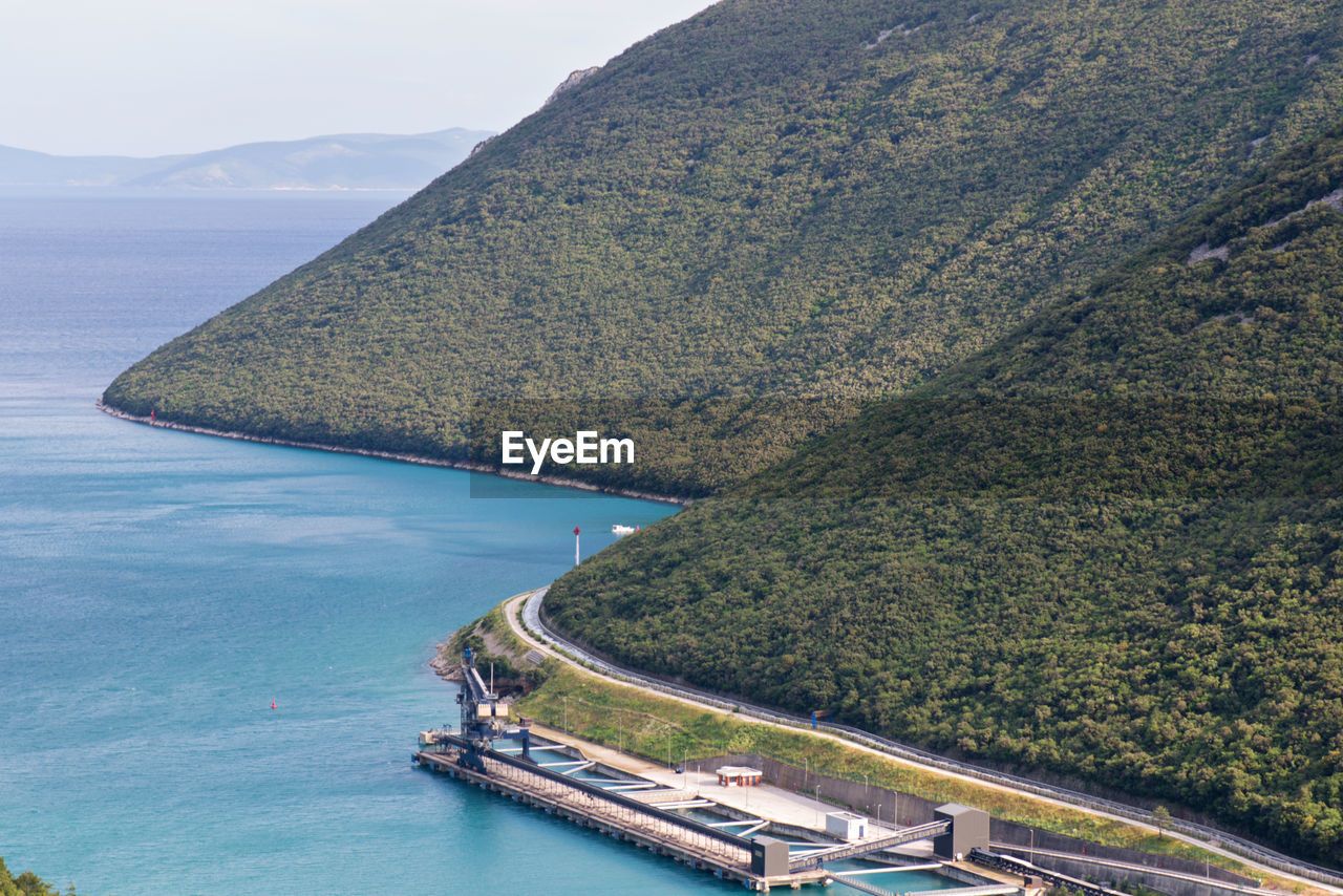 High angle view of sea by mountain against sky