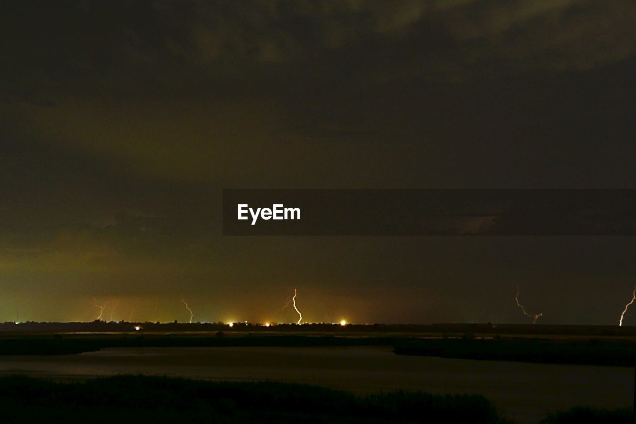 Lighting over field and lake at night