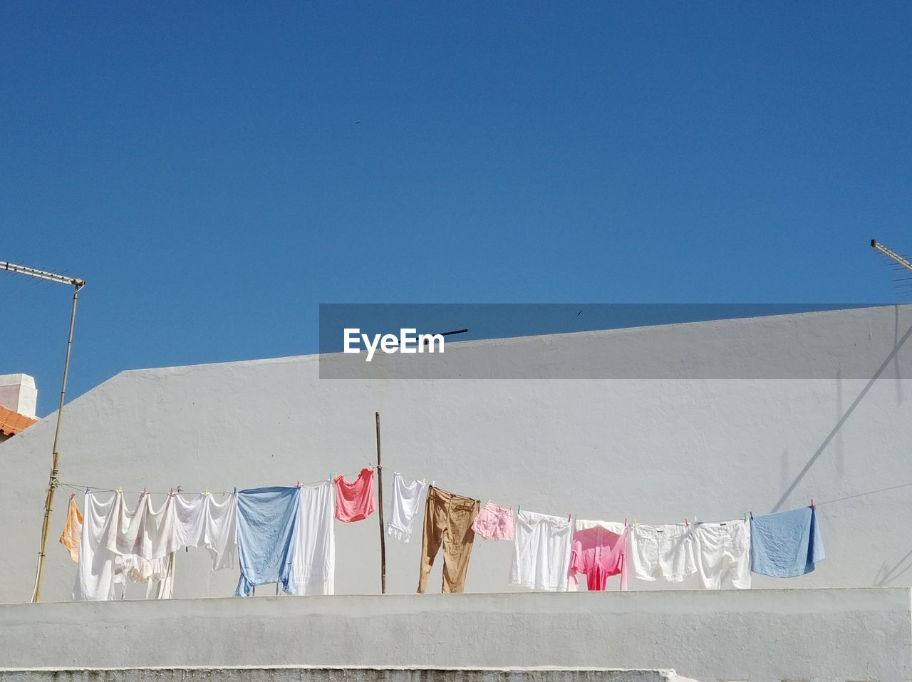 CLOTHES DRYING ON CLOTHESLINE AGAINST CLEAR BLUE SKY