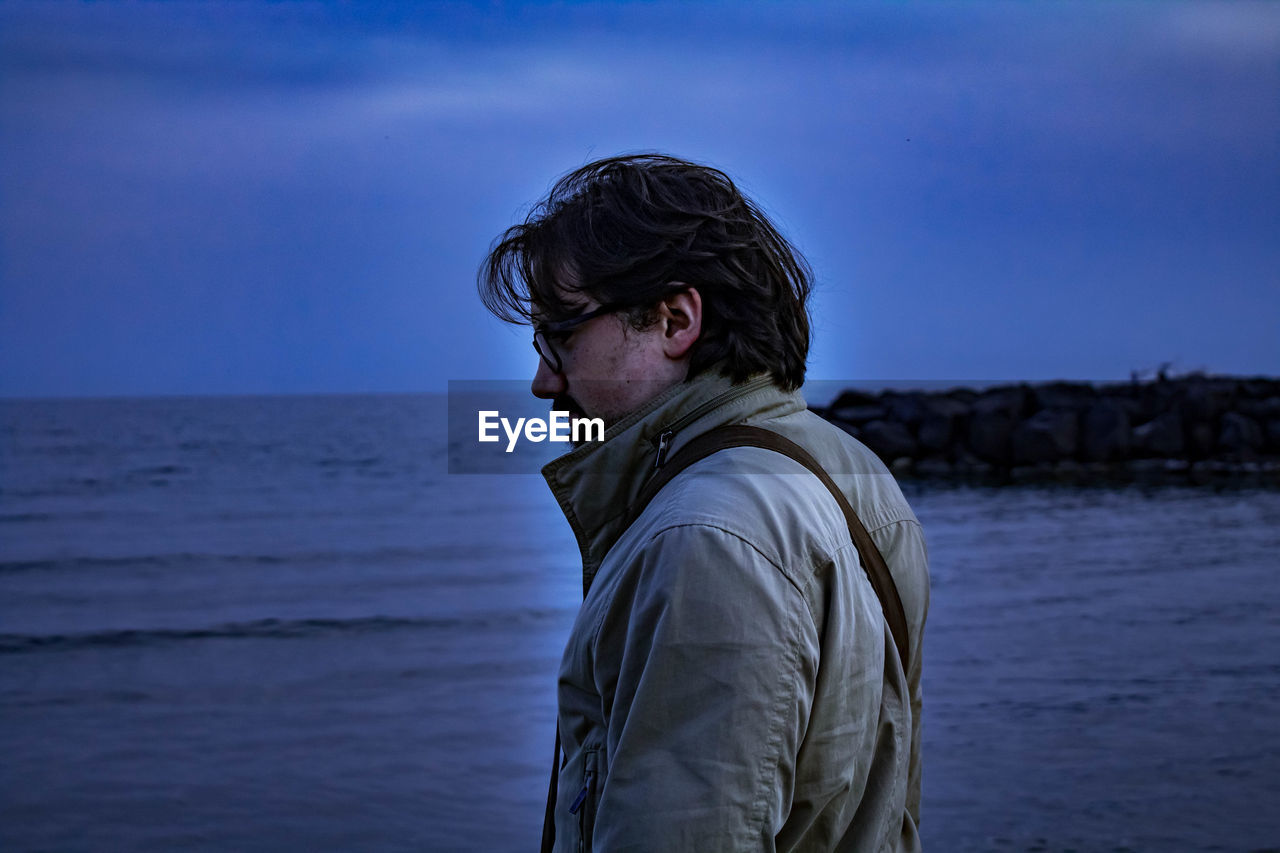 Man standing at beach during dusk