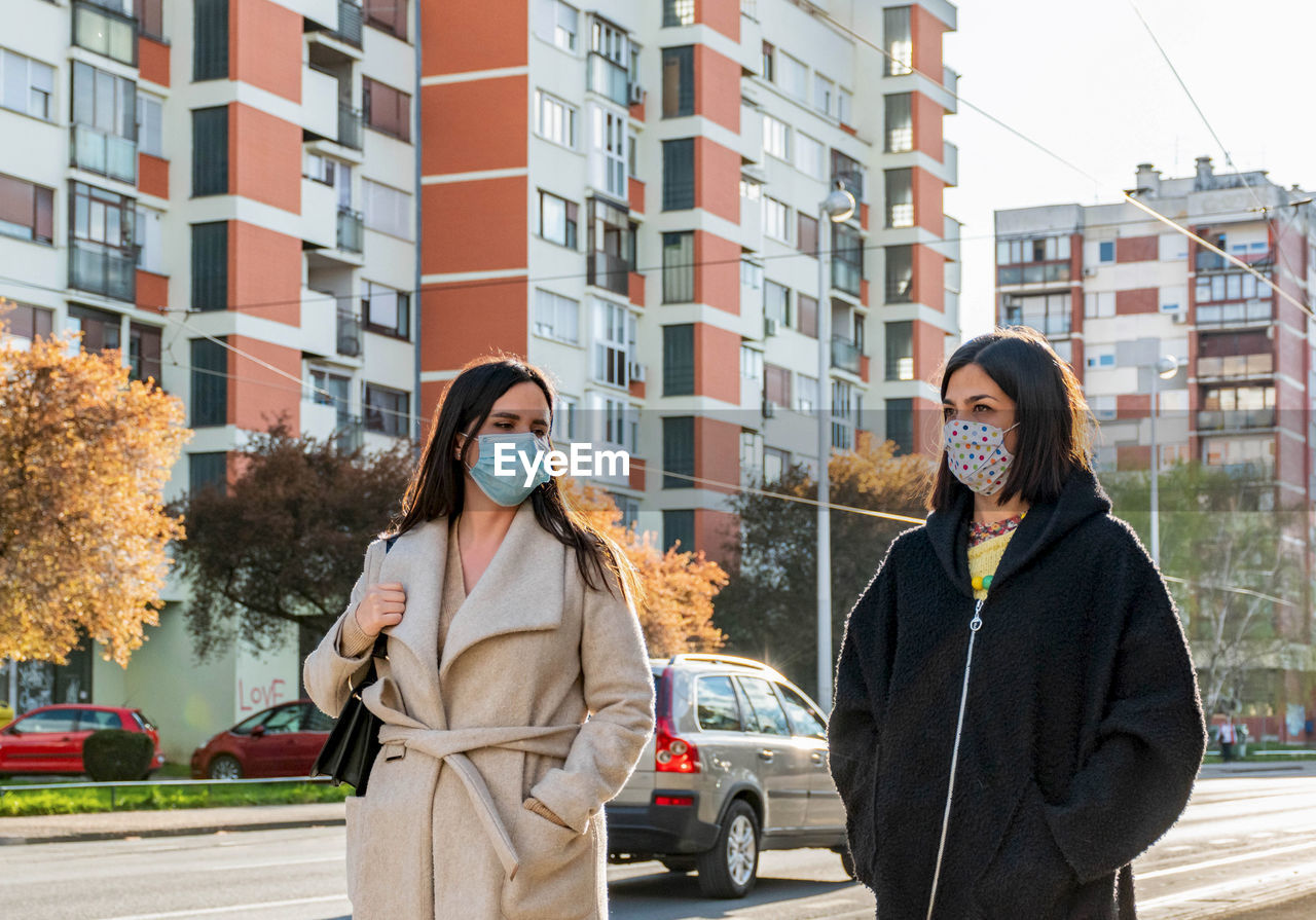 Two friends walking in city, wearing protective masks during corona virus epidemic, female, women.