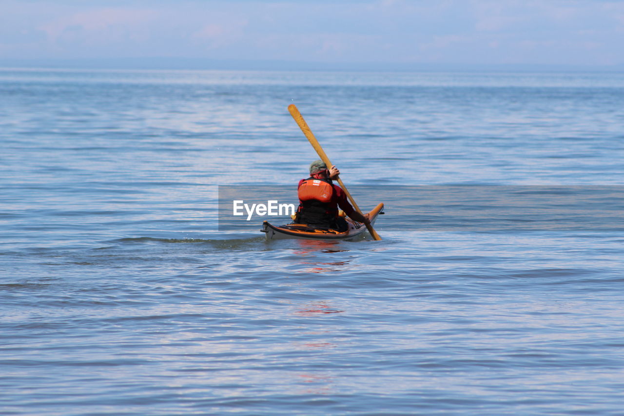 Rear view of man kayaking on lake