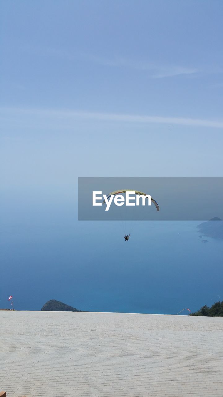 PERSON PARAGLIDING FLYING OVER LAND