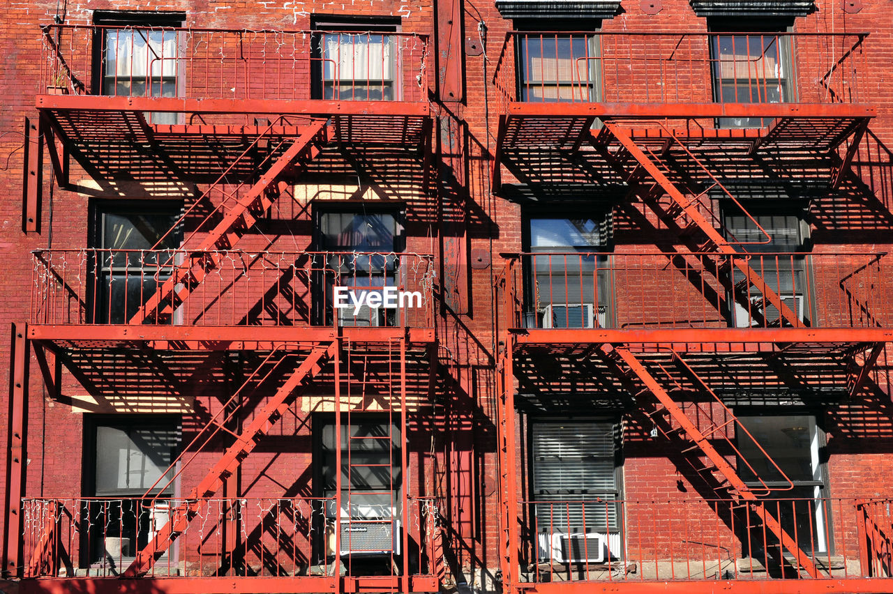 LOW ANGLE VIEW OF RED STAIRCASE AGAINST BUILDING