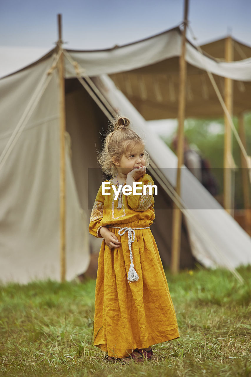 portrait of young woman standing against tent