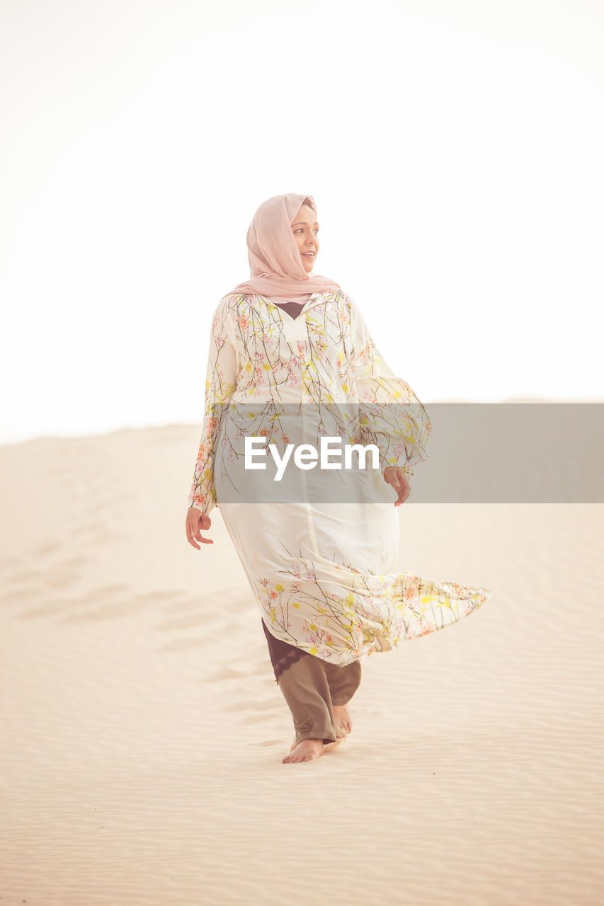 Full length of woman walking at sandy beach