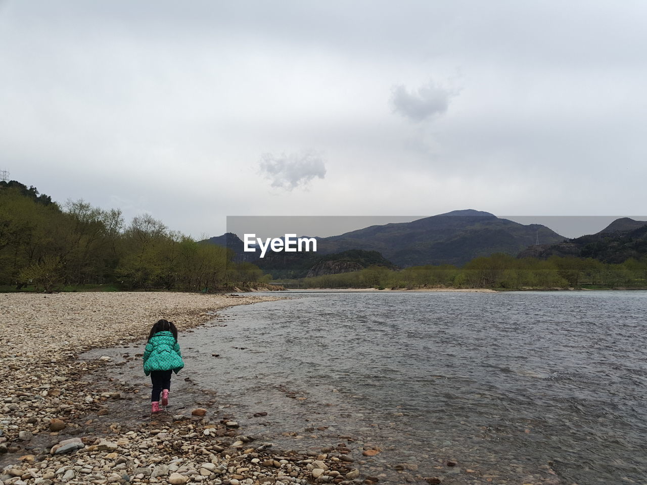 REAR VIEW OF WOMAN WALKING ON LAKE AGAINST SKY