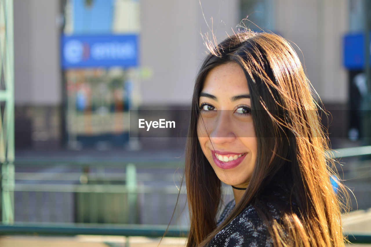 Close-up portrait of smiling young woman in city