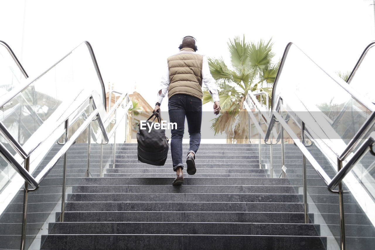 Low angle view of man climbing steps against sky