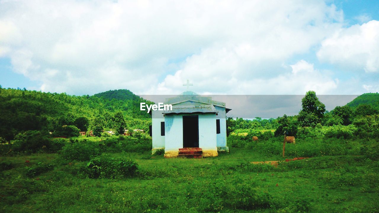 Built structure on field by trees against sky