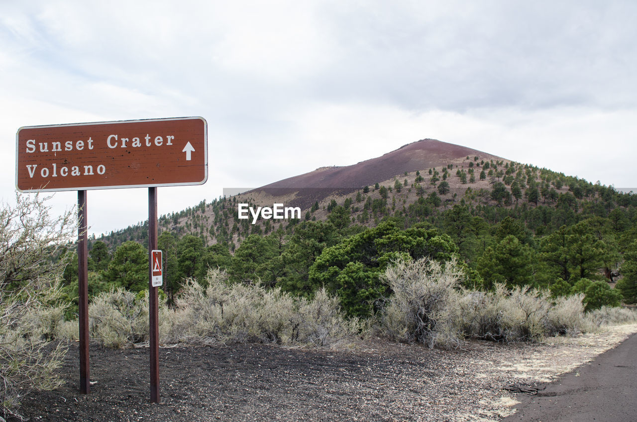 SIGN BY ROAD AGAINST SKY