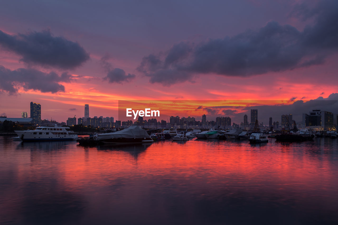 Sea and buildings against sky during sunset