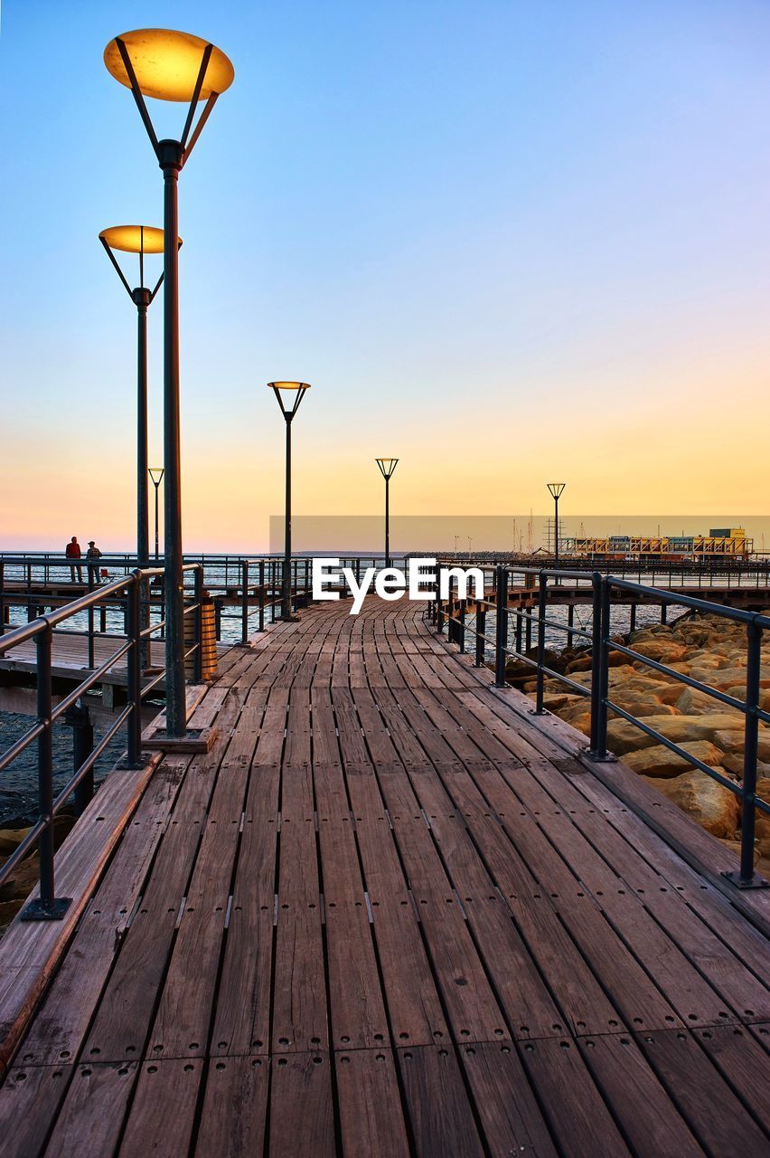 Pier over sea against clear sky during sunset