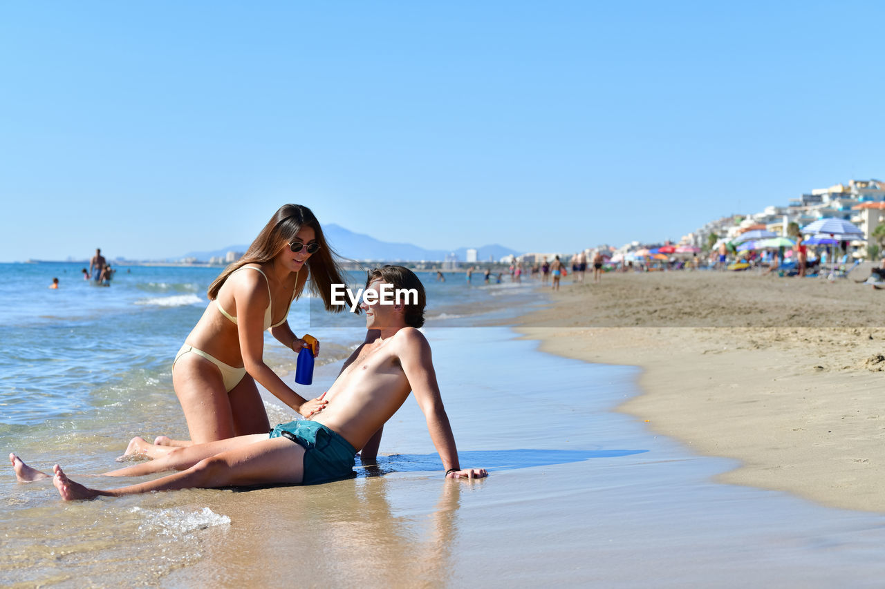 People on beach against clear sky