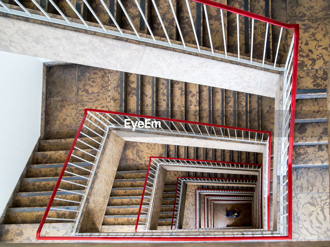 Man sitting under spiral staircase of building