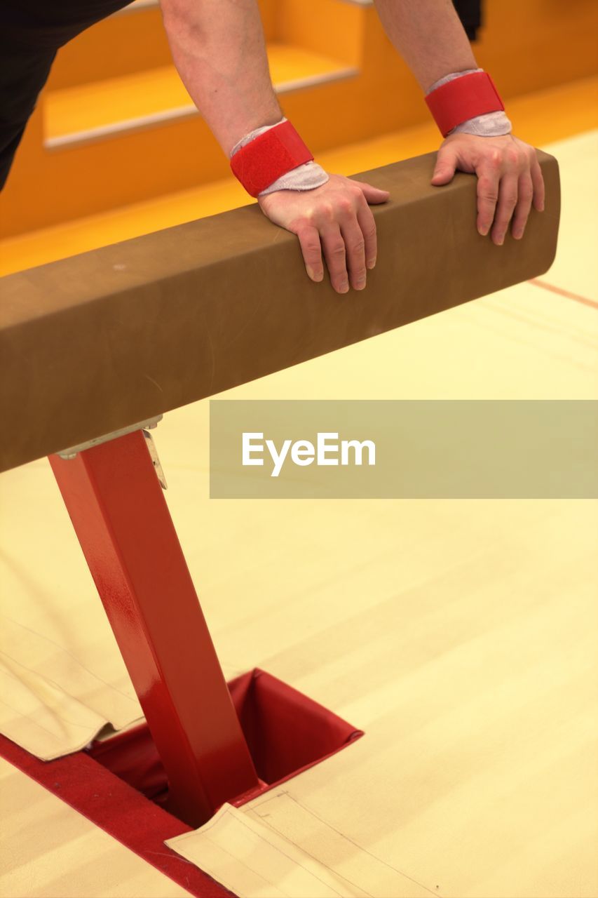 Cropped hands of person holding pommel horse in gym