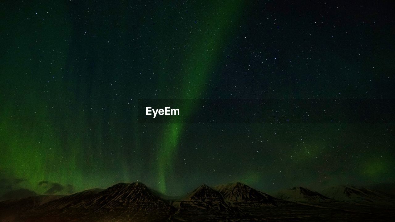 Low angle view of mountain against sky with
aurora at night