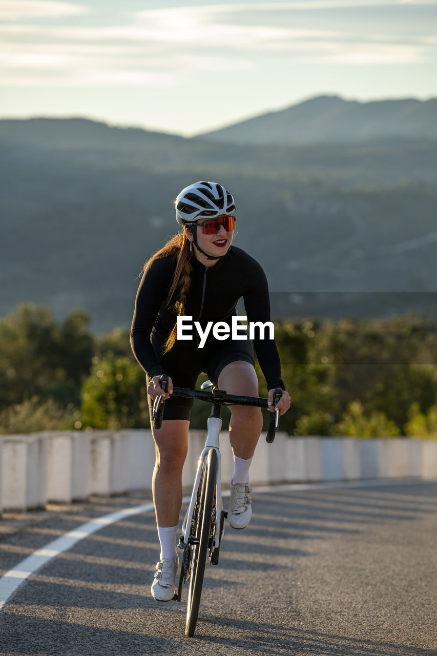 Smiling sportswoman cycling on costa blanca mountain pass in alicante, spain