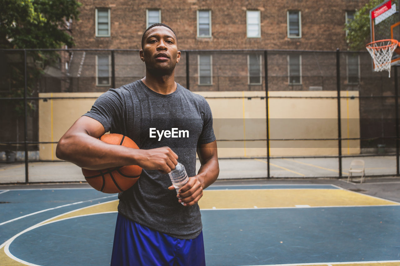 Portrait of male athlete with basketball and water bottle