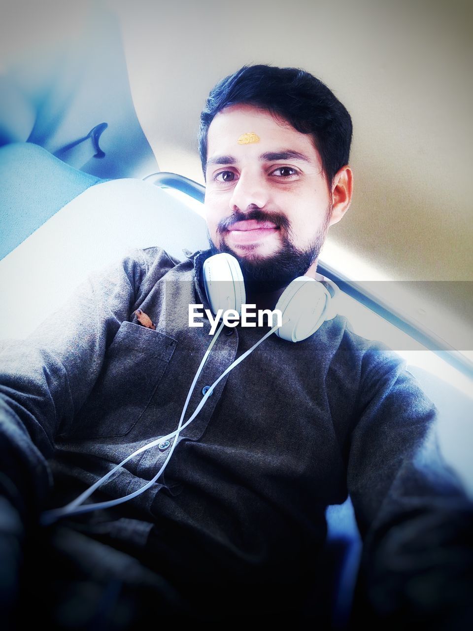 Low angle view of smiling young man wearing headphones sitting in car