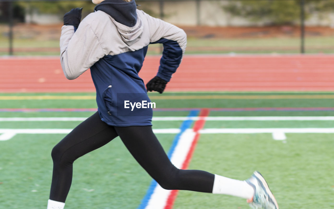 MIDSECTION OF MAN RUNNING ON FIELD