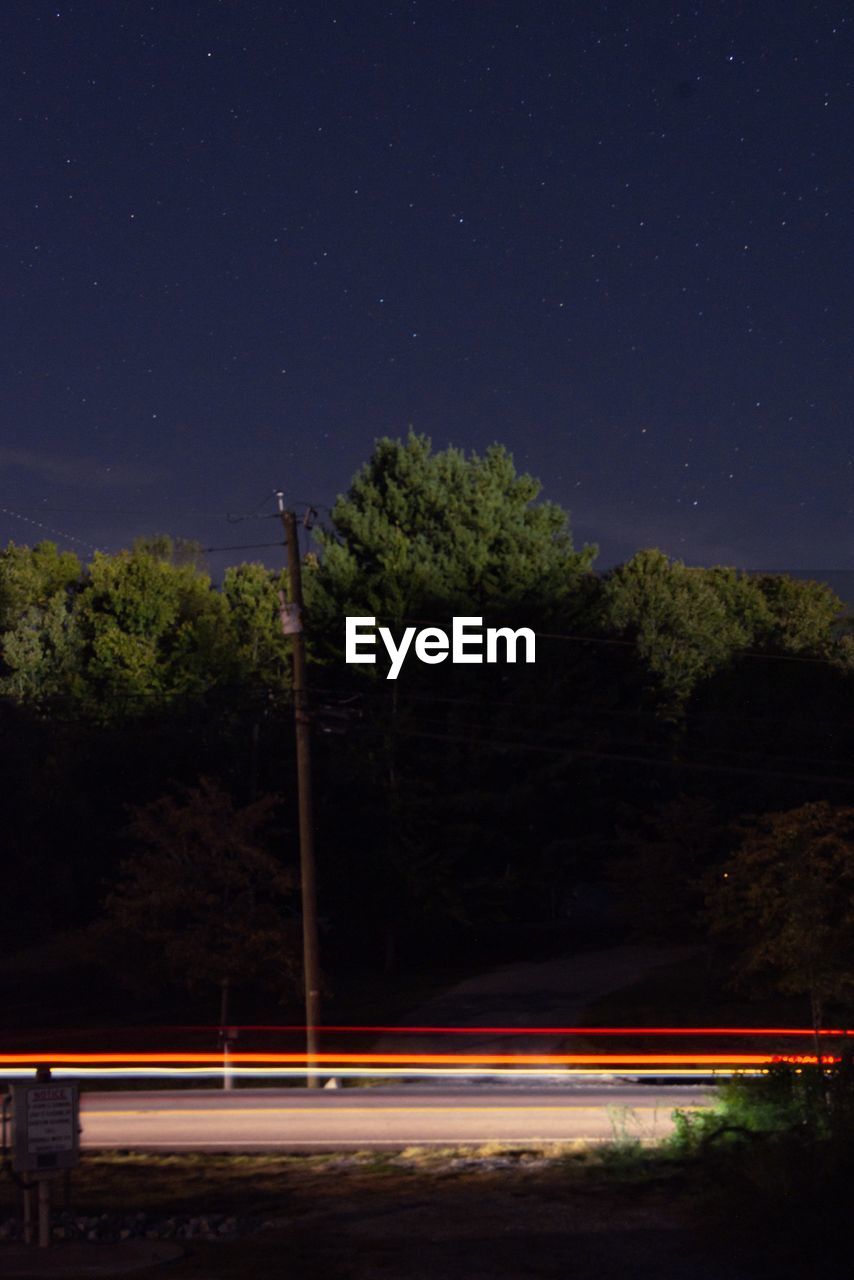 LIGHT TRAILS ON STREET IN CITY AT NIGHT