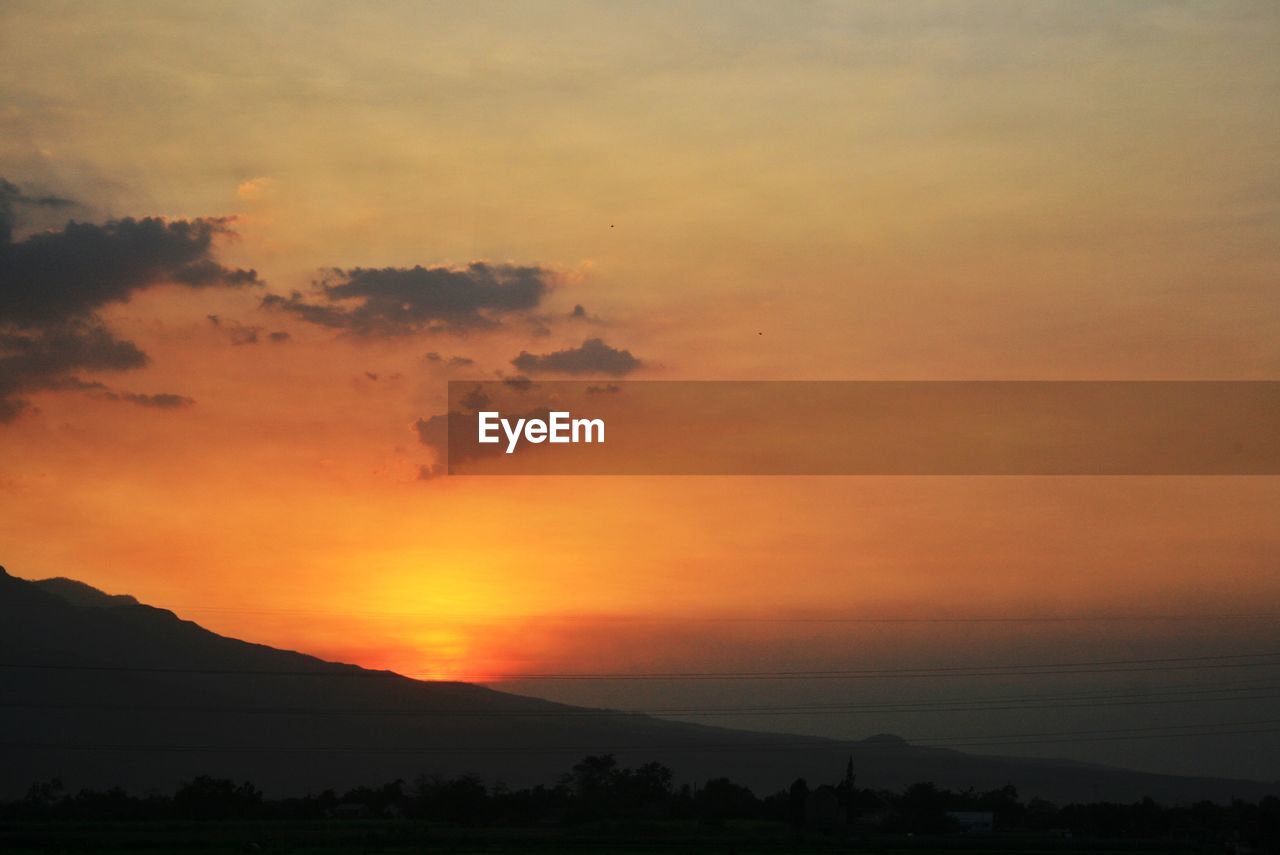 Scenic view of silhouette mountains against orange sky