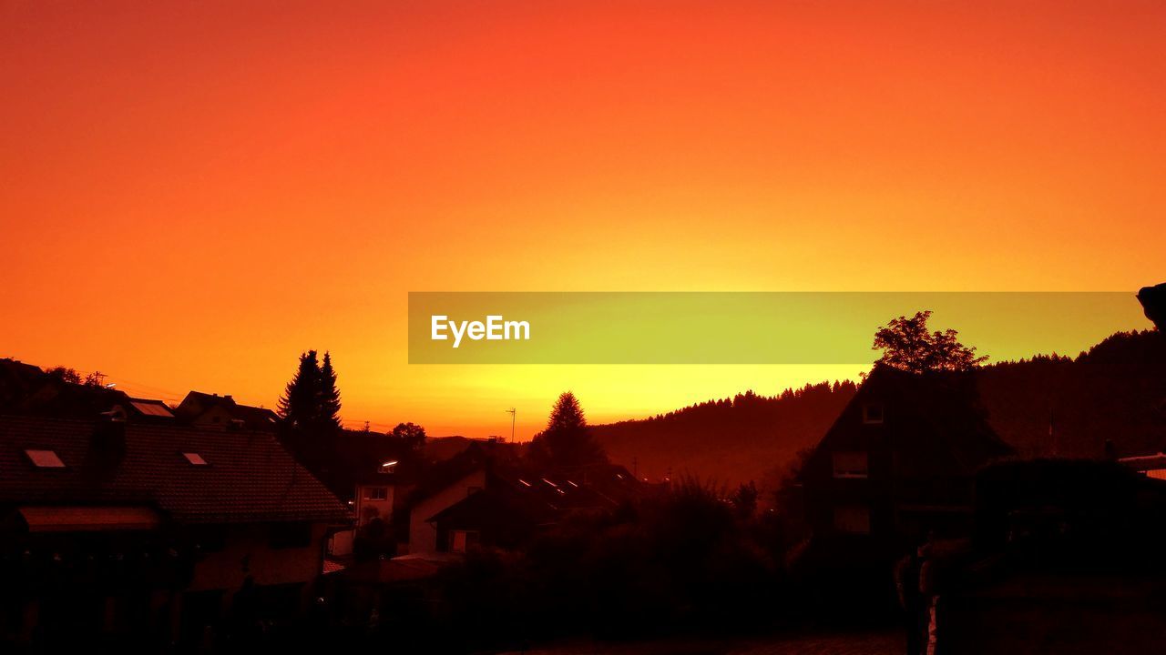 Silhouette houses against clear sky during sunset