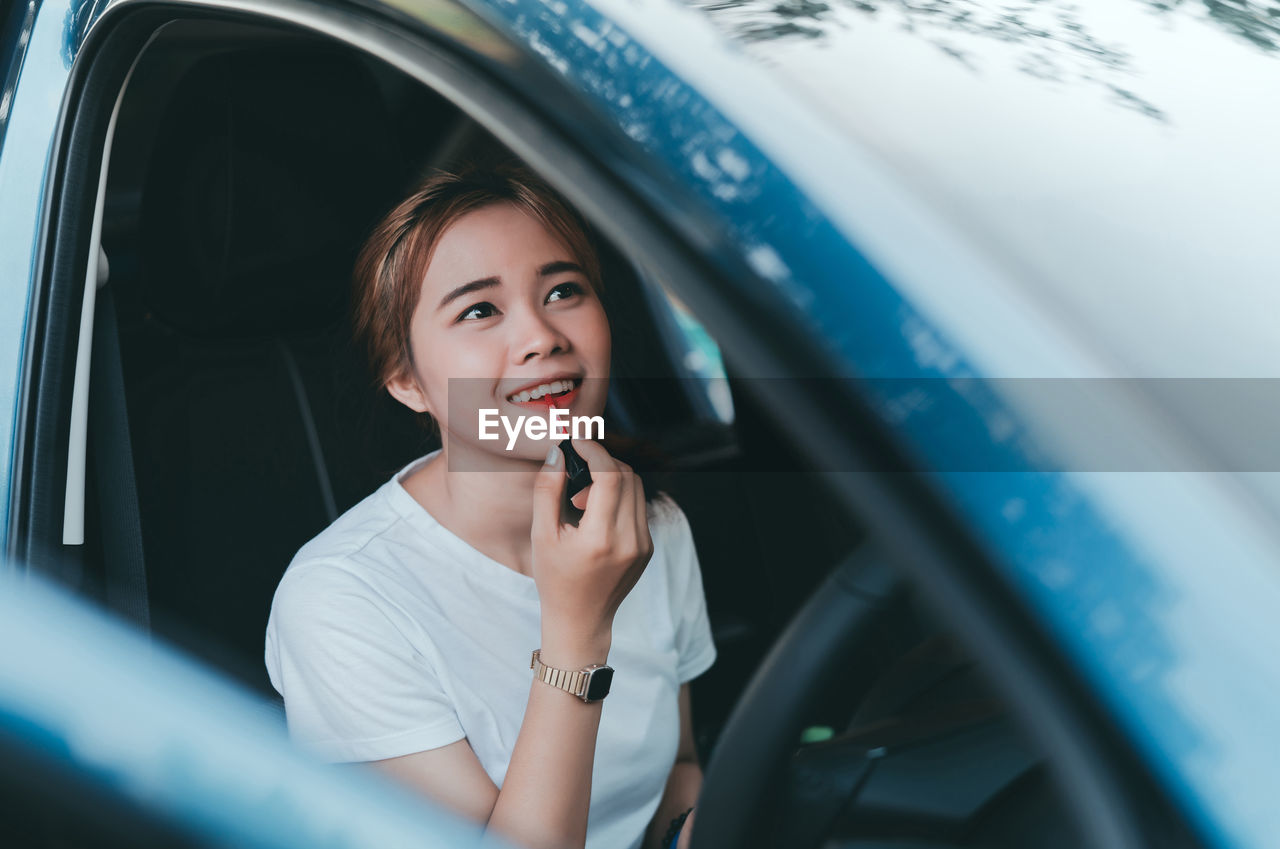 Woman applying lipstick in car