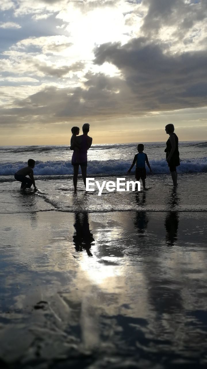 SILHOUETTE PEOPLE PLAYING AT BEACH DURING SUNSET