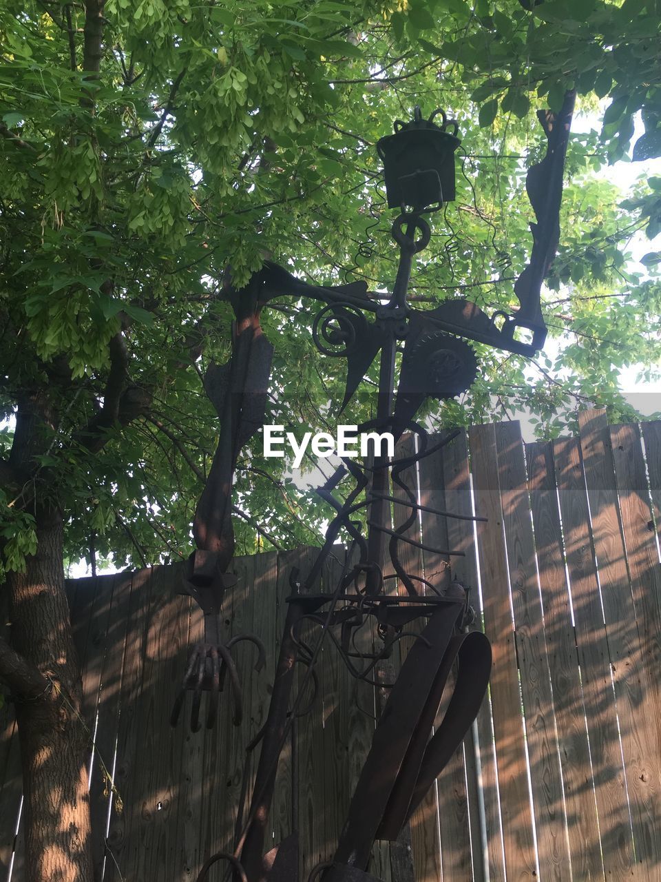 Low angle view of scrap metal sculpture against wooden fence