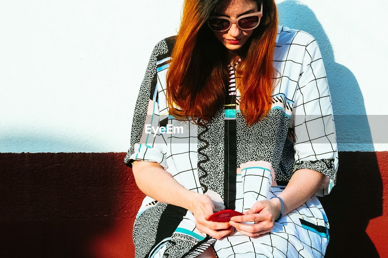 Young woman sitting against wall