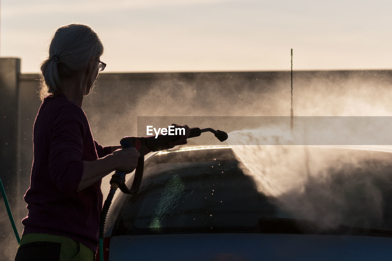 Silhouette woman washing car