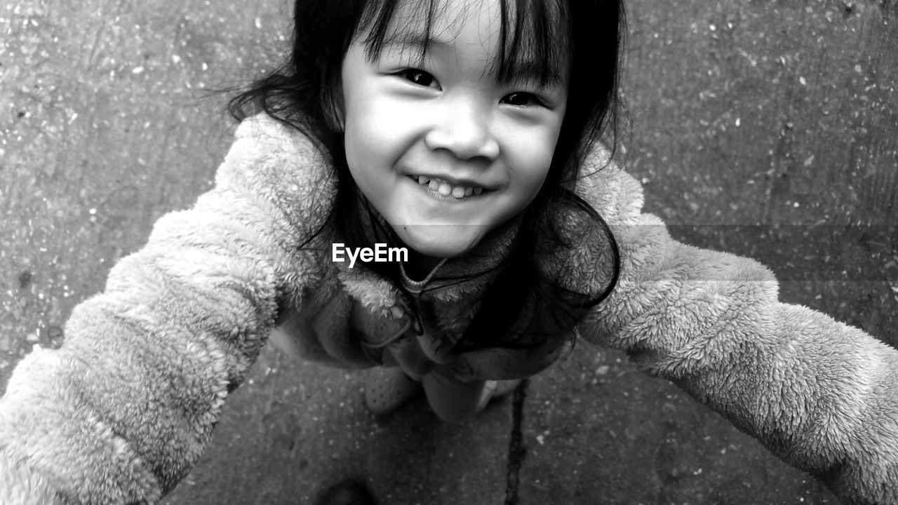 Close-up high angle portrait of cute smiling girl standing on footpath